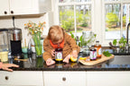 Baby with mouth over Elderberry Lemonade Mix bottle on counter