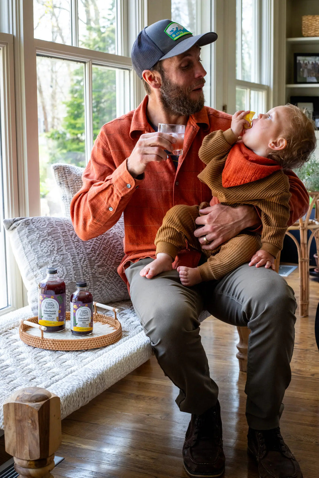 Man drinking Elderberry Lemonade Mix holding baby