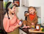 Woman owner smiling at her child licking spoon with tonic on it