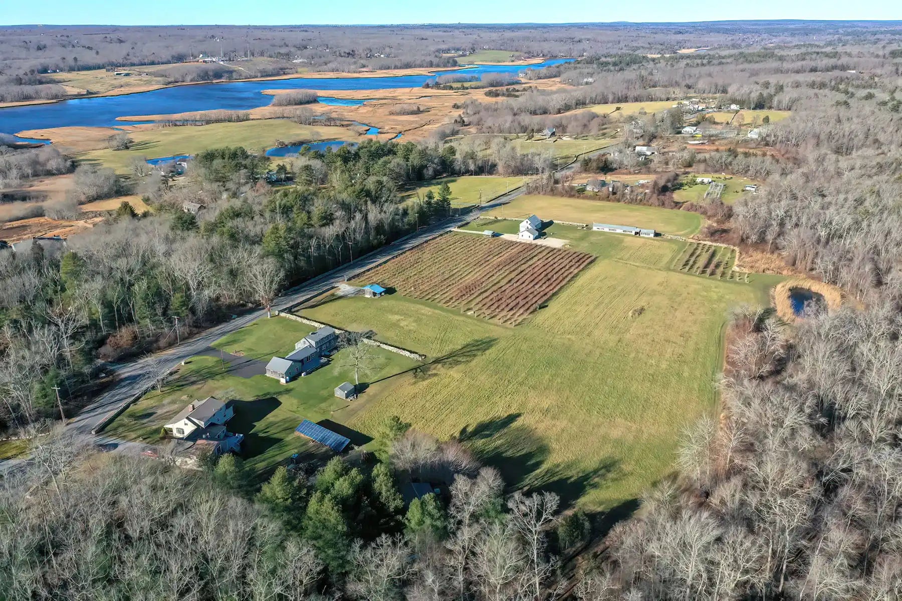 Aerial view of a rural farm with fields, trees, and a river.