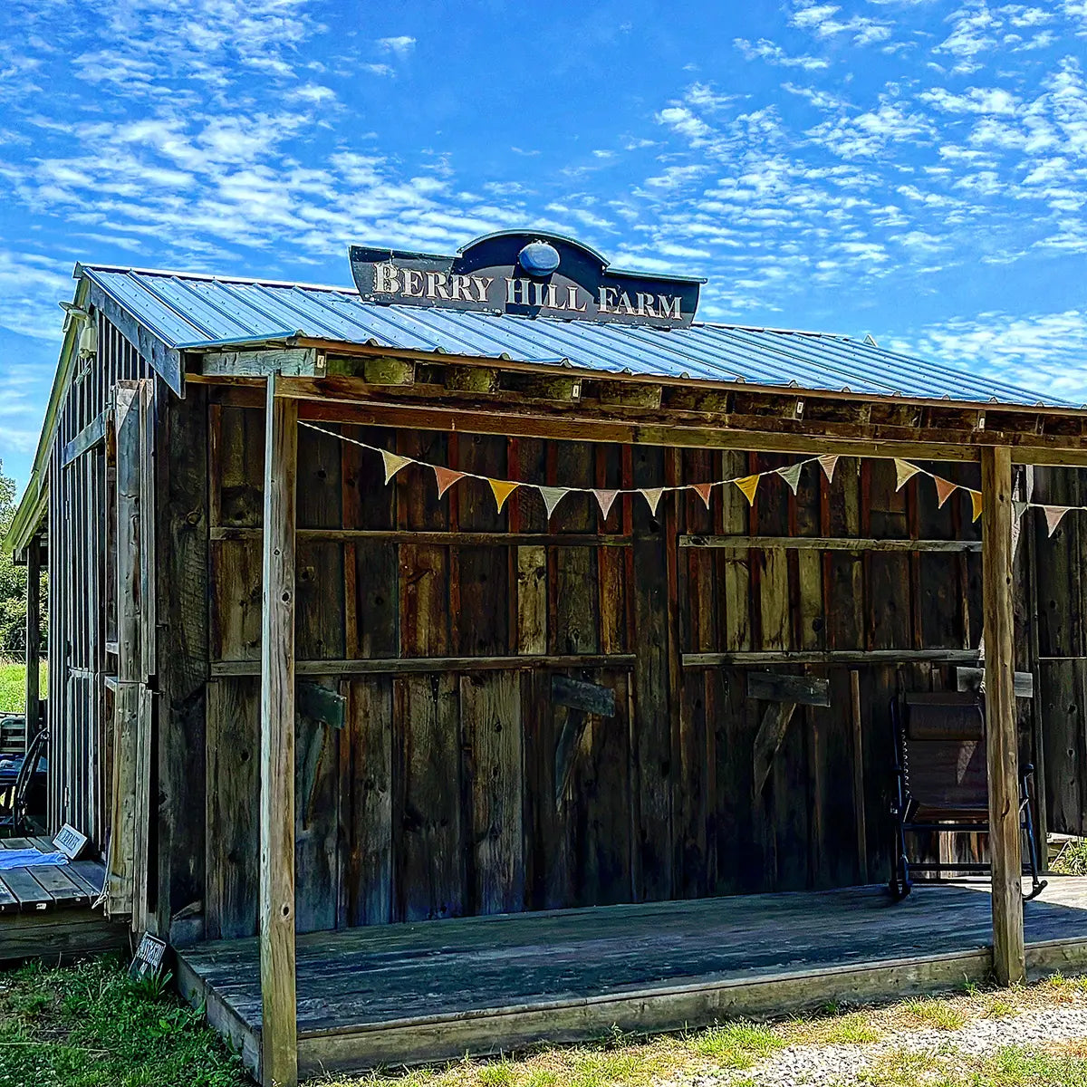 Wooden shed with 'Berry Hill Farm' sign under a blue sky
